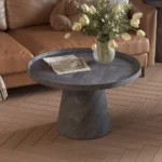 De Salontafel Donkergrijs, Roest 80 CM met een gestructureerde afwerking staat op een lichthouten visgraatvloer, met daarop een vaas met witte tulpen en een tijdschrift. Op de achtergrond staat een bruine bank gedrapeerd met een kleed.