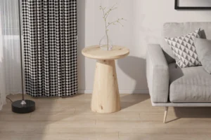 De Salontafel 45 CM, een ronde houten bijzettafel, staat naast een grijze bank met een geometrisch kussen; vlakbij hangen zwart-wit gedessineerde gordijnen, een staande lamp en in de ruimte ligt een lichte houten vloer.
