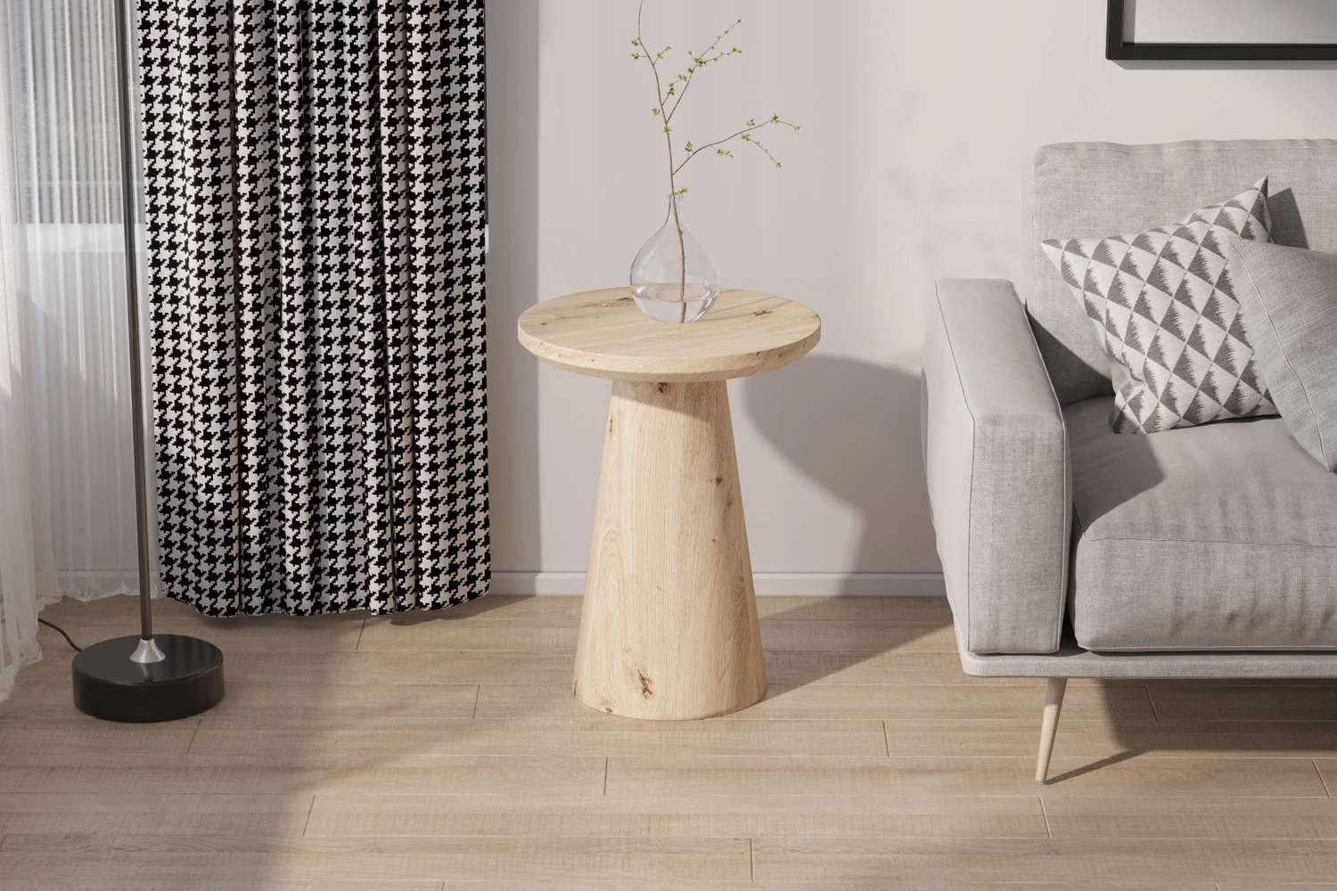De Salontafel 45 CM, een ronde houten bijzettafel, staat naast een grijze bank met een geometrisch kussen; vlakbij hangen zwart-wit gedessineerde gordijnen, een staande lamp en in de ruimte ligt een lichte houten vloer.