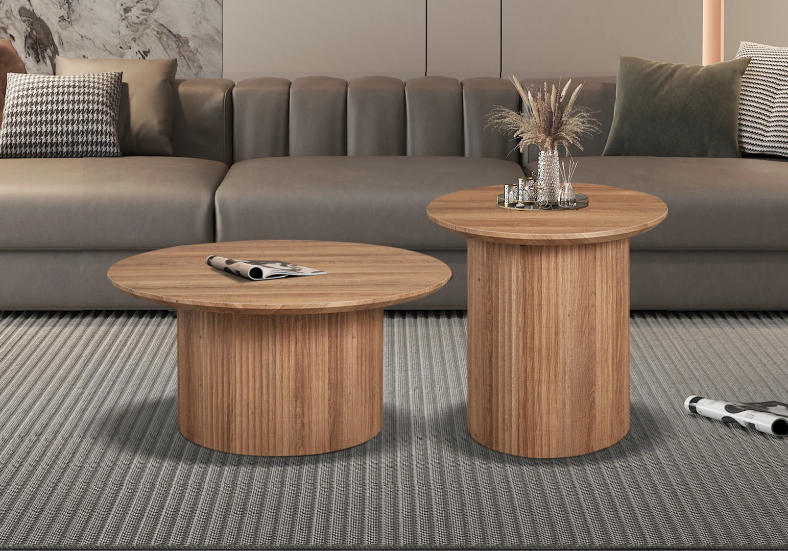 De Salontafel Roest 80 CM Rond Modern staat op een grijs vloerkleed met structuur voor een grijze bank met gedessineerde kussens. Op één tafel staat een dienblad met decor en gedroogde grassen, op de andere tafel ligt een opgerold tijdschrift.