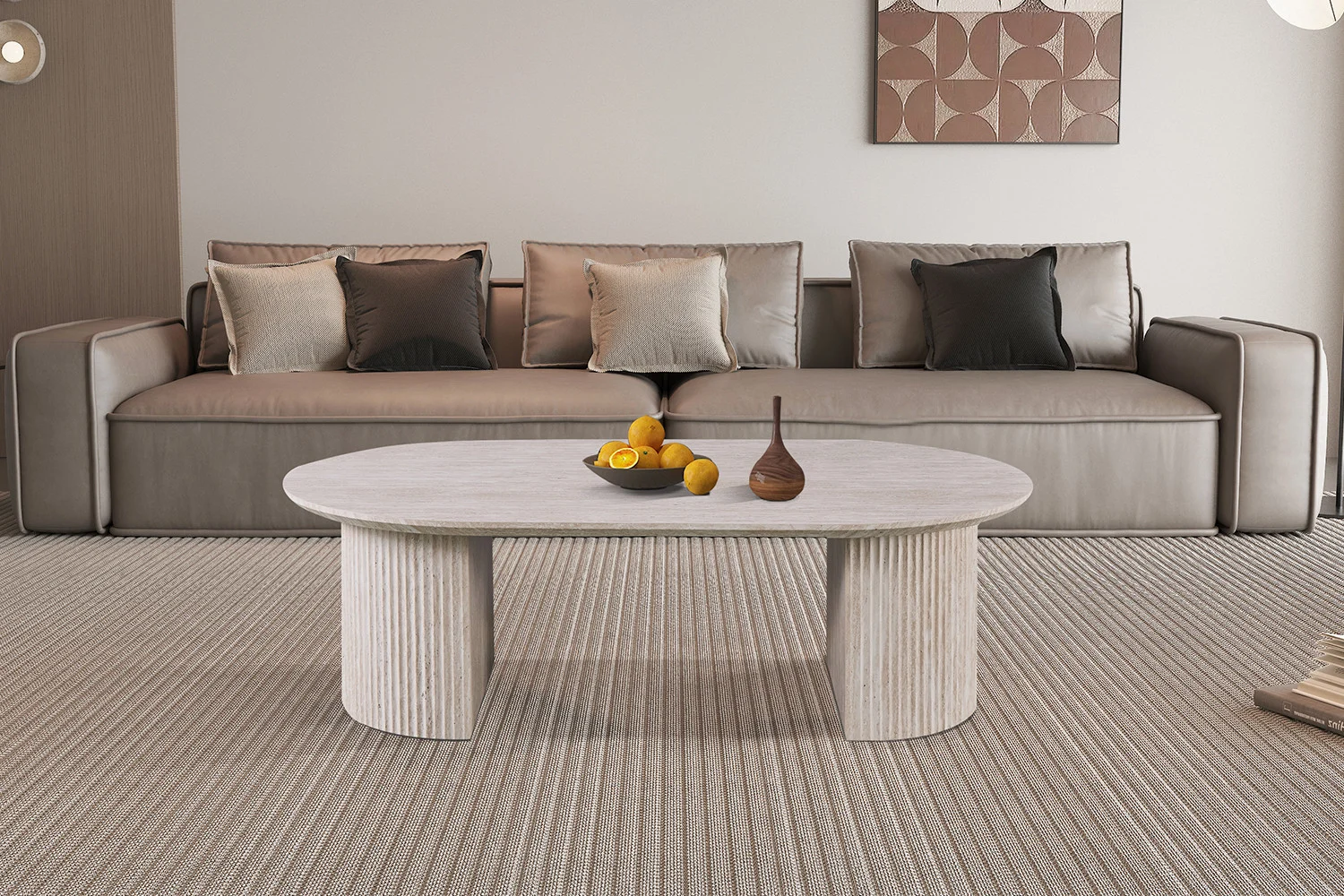 Een moderne woonkamer met een beige bank, neutrale kussens, een tapijt met structuur en de Salontafel Beige 120 CM Ovaal Travertin als salontafel met fruit en vazen. Abstracte kunst siert de muur achter de bank.