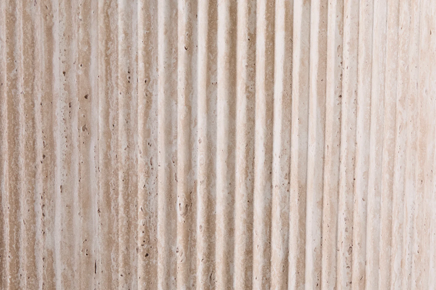 Close-up van Salontafel Beige 120 CM Ovaal Travertin, met een beige, verticaal gegroefd stenen oppervlak met ruwe textuur, natuurlijke kleurvariaties en kleine donkere vlekjes die doen denken aan klassieke gecanneleerde zuilen.