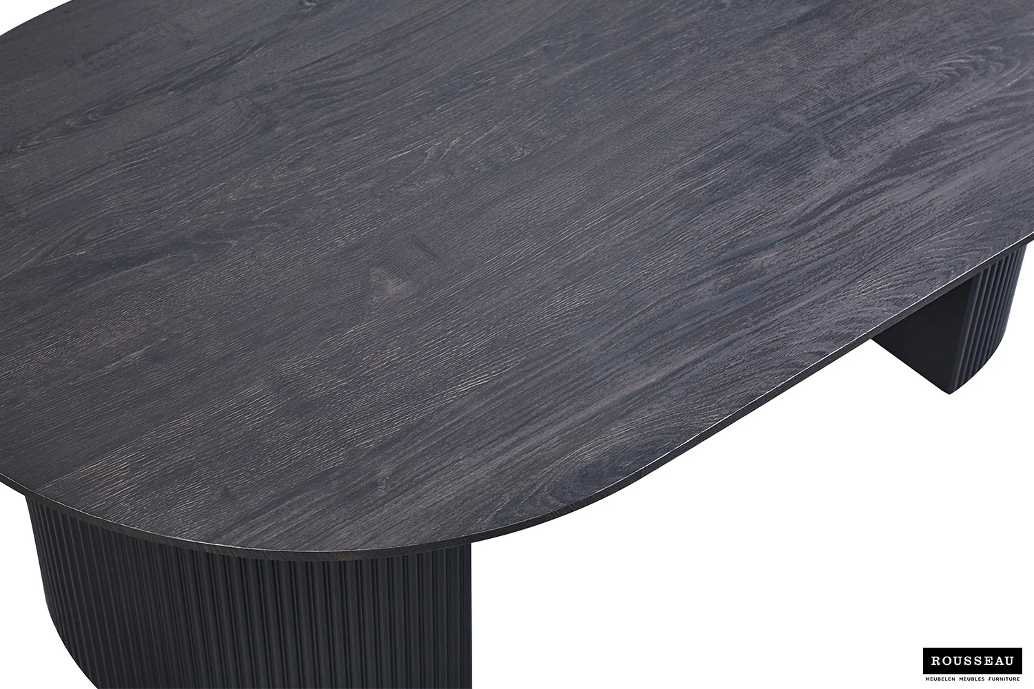 Close-up van de Salontafel 120 CM Ovaal, met een donkere houten afwerking, ovale vorm met afgeronde hoeken en een gegroefde basis. De textuur van het hout wordt benadrukt, met een klein Rousseau-logo in de rechterbenedenhoek.
