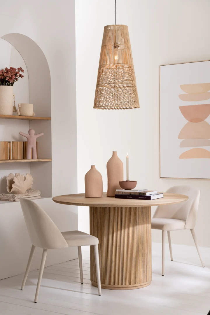 Een moderne eethoek is voorzien van de Tafel Vincent Mangohout Natuurlijk Groot, twee beige stoelen, neutrale vazen, een kaars, een geweven hanglamp, planken met decor en abstracte muurkunst in zachtroze en bruine tinten.