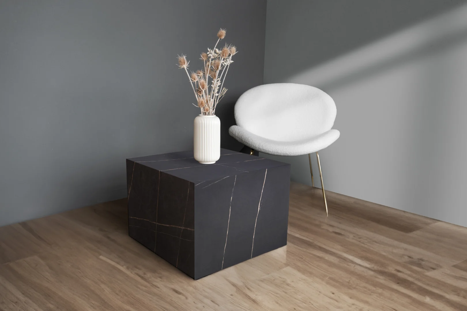 Een minimalistische kamer met een licht houten vloer, een moderne witte stoel met gouden poten en de vierkante salontafel Bijzettafel Zwart MDF Design met daarop een witte geribbelde vaas met droogbloemen. De muren zijn geschilderd in grijstinten.