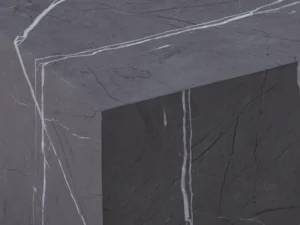 Een close-up van de Bijzettafel Grijs MDF Minimalistisch, met een donkergrijs oppervlak met prominente witte aderen over de bovenkant en zijkanten, die de scherpe hoeken en minimalistische, natuurlijke steenachtige textuur laten zien.