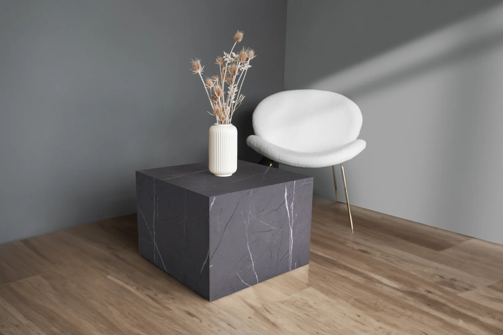 Een minimalistische kamer is voorzien van een moderne witte stoel, de Bijzettafel Grijs MDF Minimalistisch en een witte vaas met droogbloemen, allemaal tegen grijze muren en een lichte houten vloer.