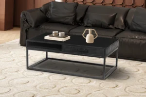 Een moderne woonkamer met de Salontafel Zwart Mangohout met boeken, kaarsen en een vaas, op een vloerkleed met licht patroon voor een zwarte bank.