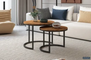 De Salontafel Mangohout Minimalistisch, met ronde houten bladen en zwarte metalen poten, staat op een licht gestreept tapijt in een moderne woonkamer met een witte bank, verschillende kussens en decoratieve planten en schalen op de tafels.