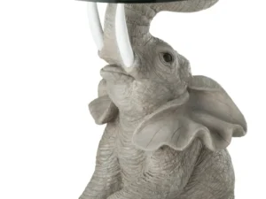 De Bijzettafel Greige, Grijs 63 CM Glas is een ronde glazen bijzettafel met een gedetailleerd beeld van een grijze olifant met opgeheven slurf, zichtbare slagtanden en grote gespreide oren als basis.