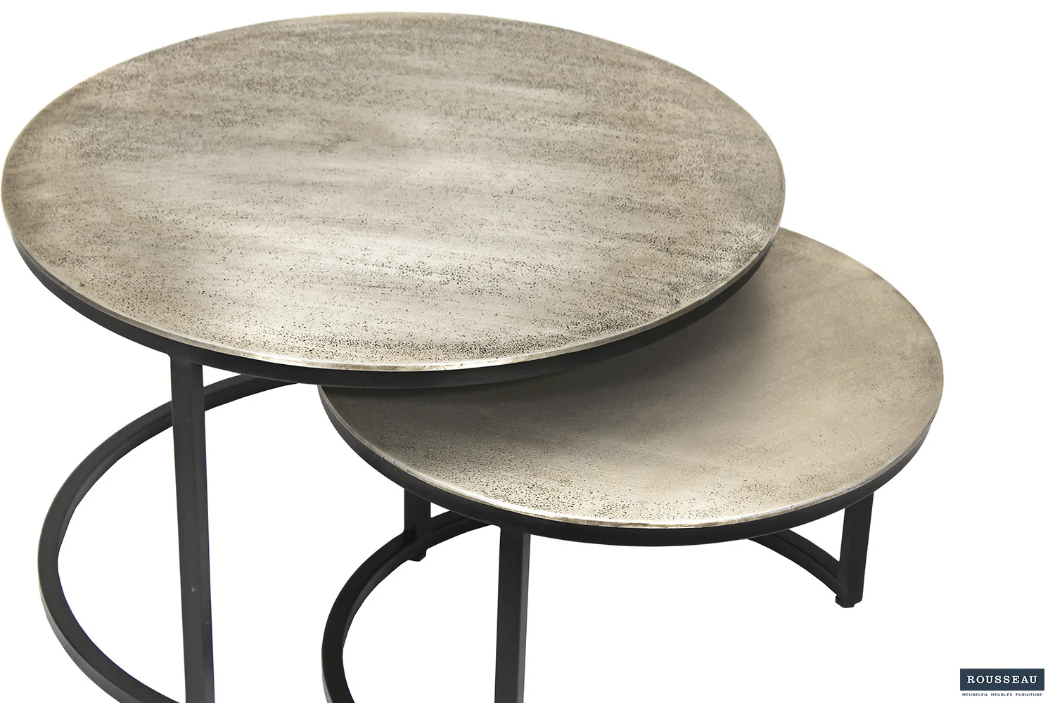 De Salontafel Zilver Compact bestaat uit twee ronde, metalen nesttafels met een zwart onderstel. De geborstelde, lichtgrijze oppervlakken vullen het ontwerp aan en de kleinere tafel kan gedeeltelijk onder de grotere tafel worden geschoven om ruimte te besparen.