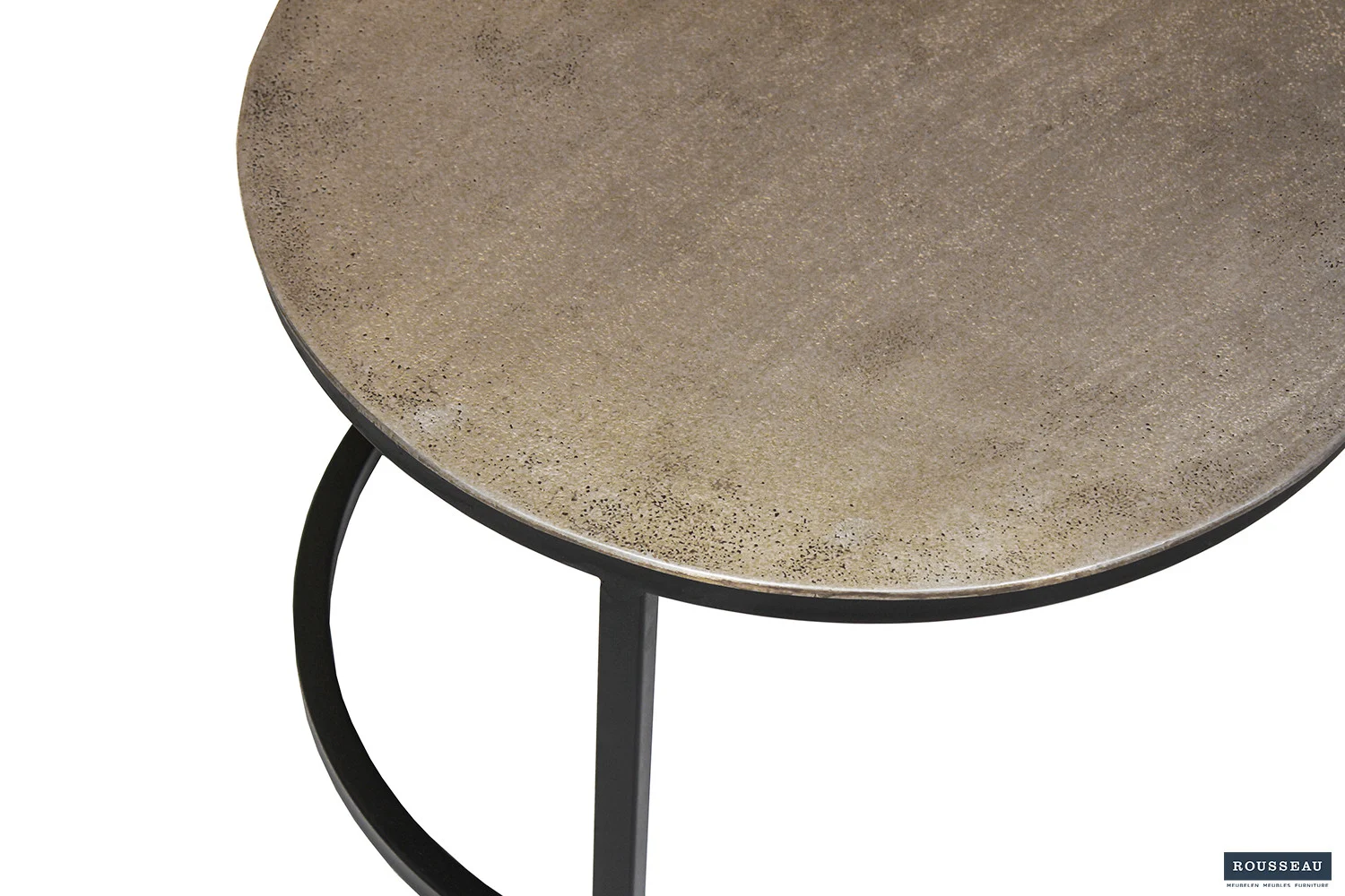 Een close-up van de Salontafel Zilver Compact toont het ronde tafelblad met een gestructureerd metalen oppervlak en een zwart metalen frame, gedeeltelijk zichtbaar tegen een witte achtergrond.