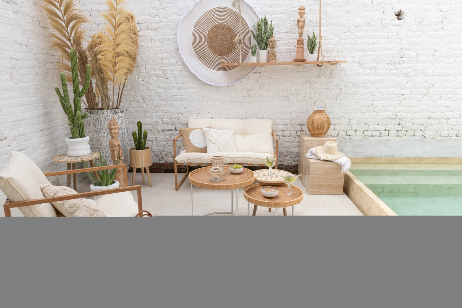 Een gezellig terras met witte muren, planten in potten en de Set van 3 bijzettafel patronen 3 poten Bamboe/Hout Natuur/Wit, met houten accenten en een klein zwembad voor een ontspannen, boho-chique sfeer.