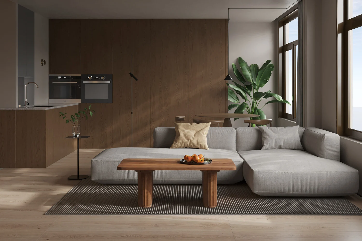 Een moderne woonkamer met een grijze sectionele bank, de Salontafel Roest Mangohout Tijdloos met fruit, een gestreept vloerkleed, grote ramen, een groene plant en een minimalistische keuken op de achtergrond met ingebouwde ovens.