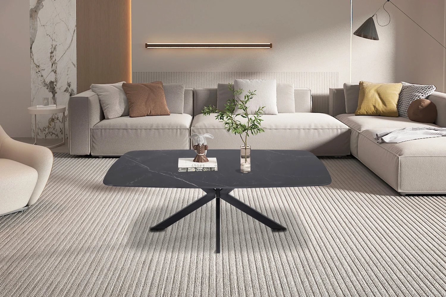 Een moderne woonkamer met een beige zitbank, decoratieve kussens en de Salontafel Zwart 130 CM Ovaal Steen met boeken en een vaas met groen, allemaal op een licht gekleurd vloerkleed met textuur.