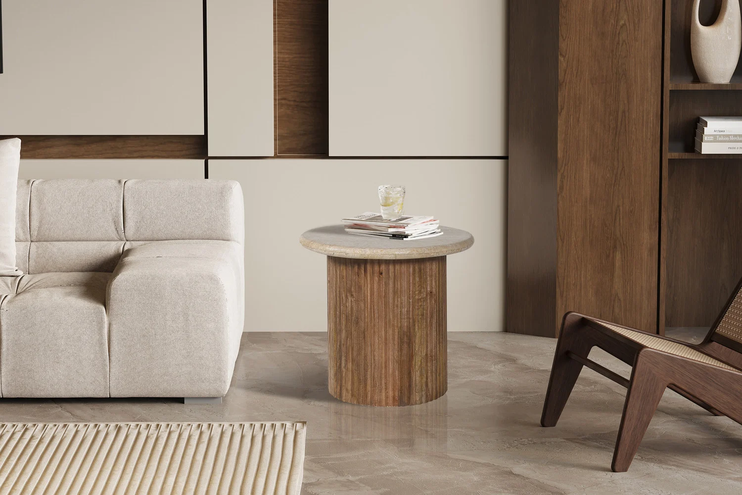 In een moderne woonkamer staat de 'Louis' 50 cm mangohout met travertin beige bijzettafel met een drankje en boeken, naast een beige bank, houten stoel, lichte geometrische wandpanelen, stenen vloer en een geribbeld vloerkleed.