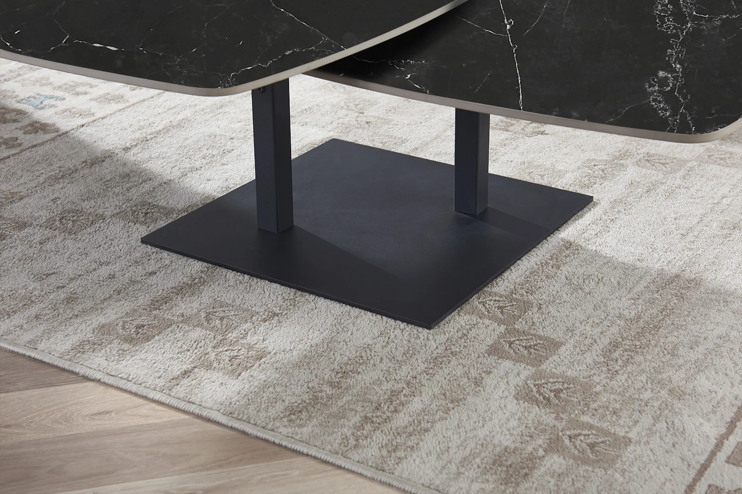 Een close-up van de Salontafel Zwart Rond Steen, een moderne zwarte ronde stenen salontafel, staand op een beige gedessineerd tapijt op een houten vloer.