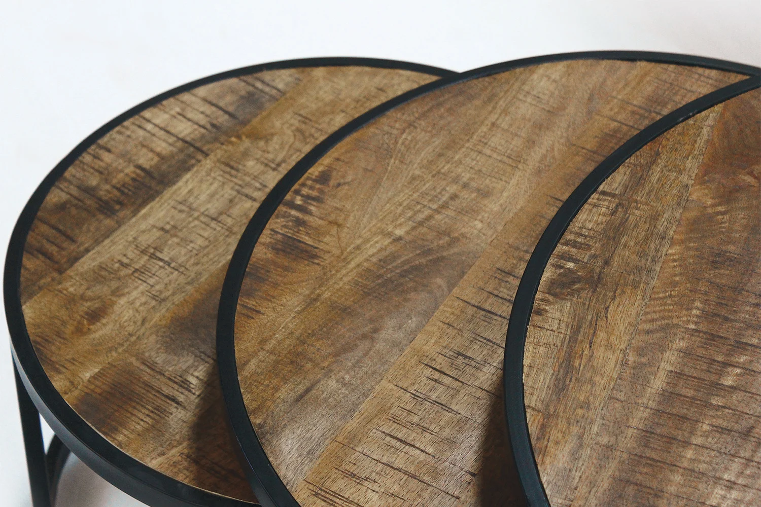 Close-up van drie overlappende tafelbladen van Salontafel Mangohout Klassiek met donkere metalen randen, die de natuurlijke houtnerf en textuur benadrukken tegen een lichte achtergrond.