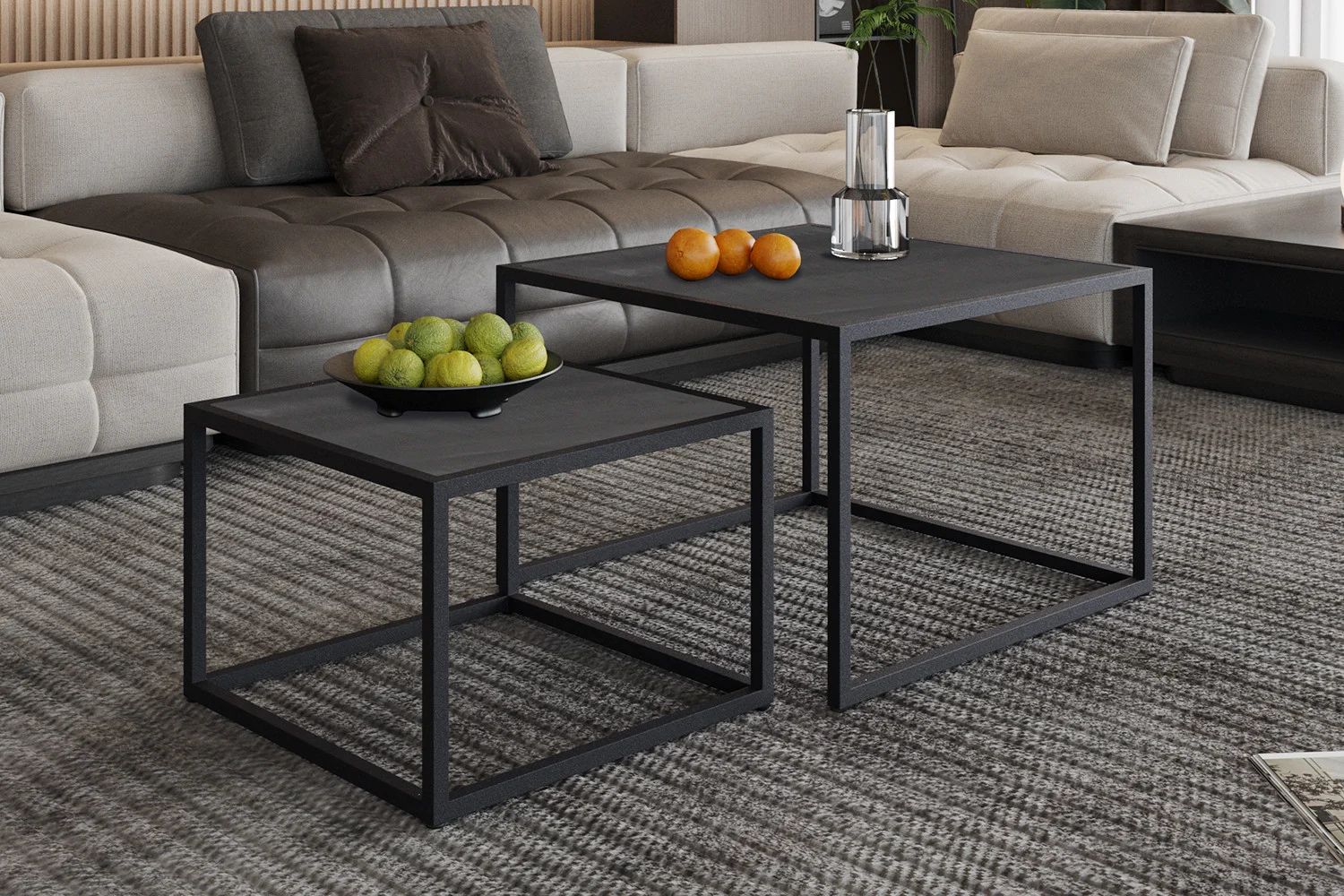 Een Salontafel Zwart Mangohout Compact staat op een tapijt met grijs patroon, met daarop een schaal met groene appels en peren, terwijl een andere een glazen vaas met een kaars en wat sinaasappels vasthoudt. Een beige sofa verschijnt op de achtergrond.