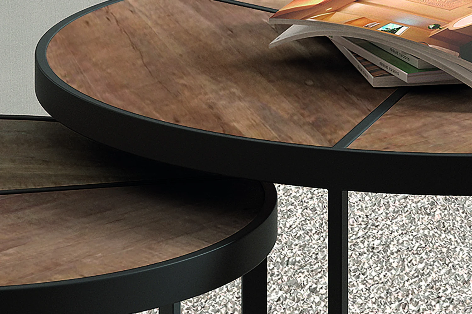 Een close-up van twee Salontafel Mangohout Compact nesttafels met donkere metalen frames en houten bladen. Op de grotere tafel ligt een tijdschrift en beide staan op een tapijt met structuur.