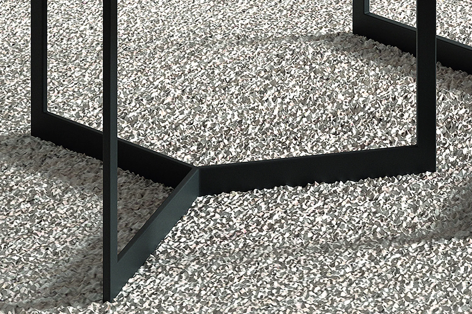 Close-up van de zwarte metalen poten van Salontafel Mangohout Compact die geometrische vormen vormen op een gestructureerd, lichtgrijs grindoppervlak.