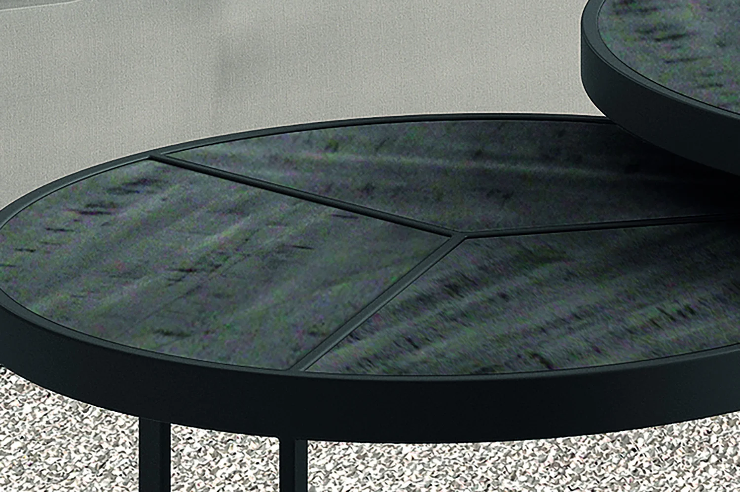 Close-up van twee overlappende Salontafel Zwart Mangohout Design tafels met een tijdloos design, ronde zwarte bladen en mat metalen onderstellen, tegen een lichte achtergrond en een gespikkelde vloer.