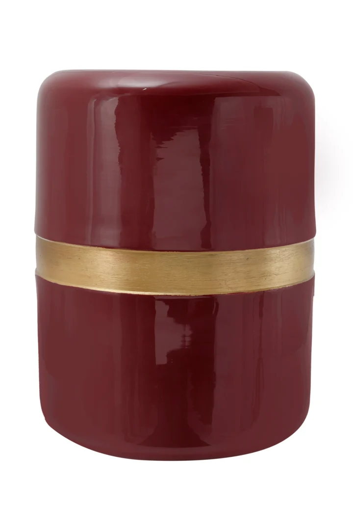 Een glanzende, dieprode Bijzettafel Rond Ijzer Chique met gladde, cilindrische zijden en een horizontale gouden band die het midden omcirkelt.