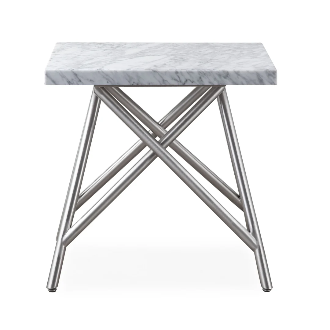 De Koraal bijzettafel in marmer heeft een modern rechthoekig wit marmeren blad en kruisende zilverkleurige metalen poten in een geometrisch, kriskras ontwerp.