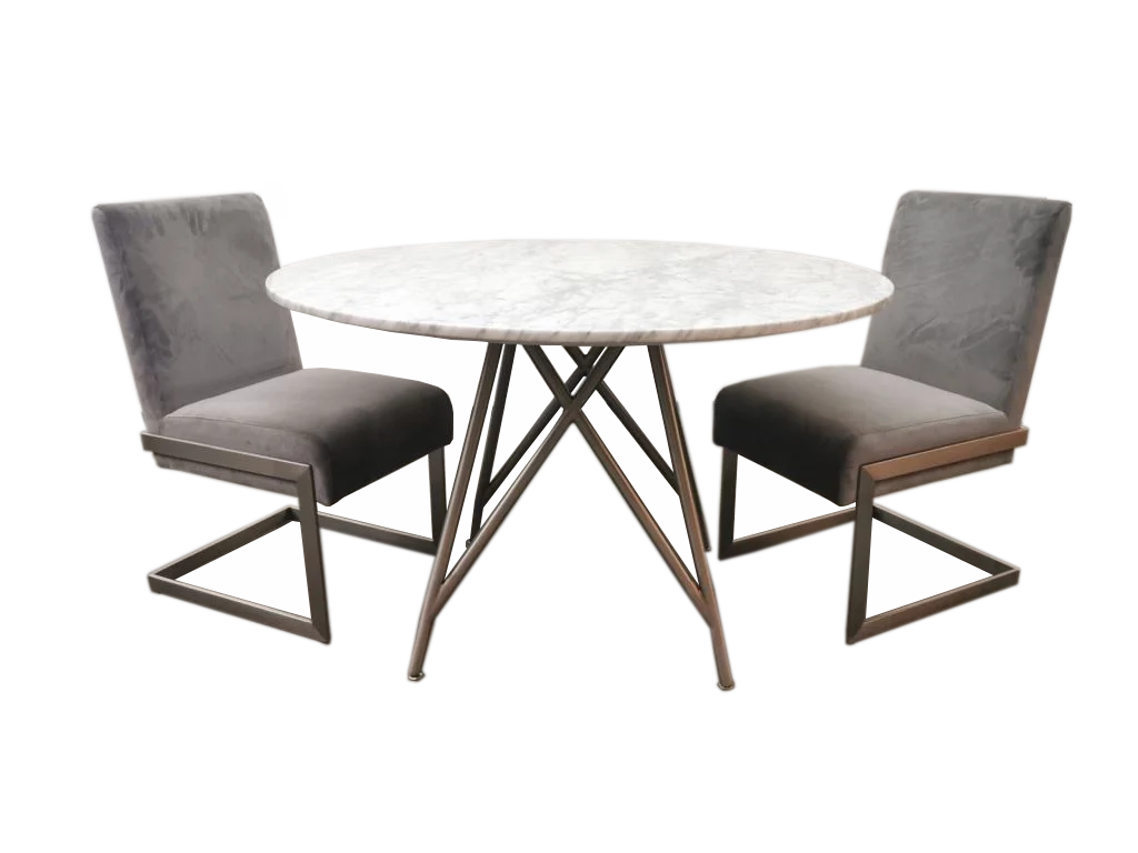 A Ronde eettafel van koraal in marmer en geborsteld roestvrij staal is omgeven door twee grijze, gestoffeerde stoelen met metalen poten aan weerszijden.