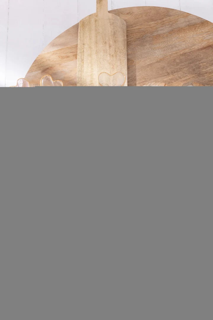 De Salontafel 80 x 34 CM Rond Mangohout is afgebeeld op een lichte achtergrond met een houten snijplank met een hartvormige uitsnede er tegenaan.