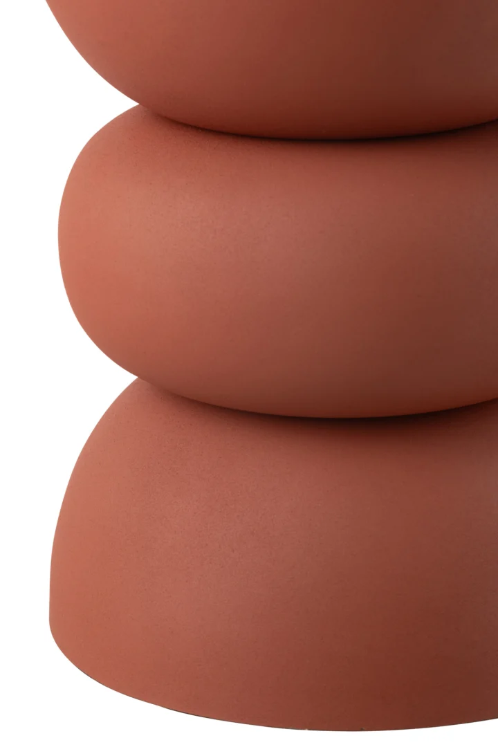 Close-up van de Bijzettafel Lise IJzer Roest: drie verticaal gestapelde, gladde, ronde vormen met een matte terracotta afwerking, die lijken op abstracte stenen of kiezels, tegen een witte achtergrond.