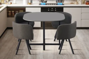 In een moderne keuken staat de Tafelset 'Eva' Grijs - een vierkante grijze tafel met vier donkergrijs gestoffeerde stoelen - opgesteld op een licht marmeren vloer, met op de achtergrond het aanrecht en de apparatuur.