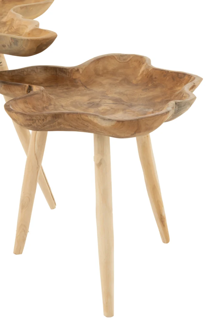 De Bijzettafel 60 x 60 CM Teakhout is een klein houten tafeltje met een natuurlijk bladvormig blad en drie slanke poten. Een soortgelijke tafel is gedeeltelijk op de achtergrond te zien.