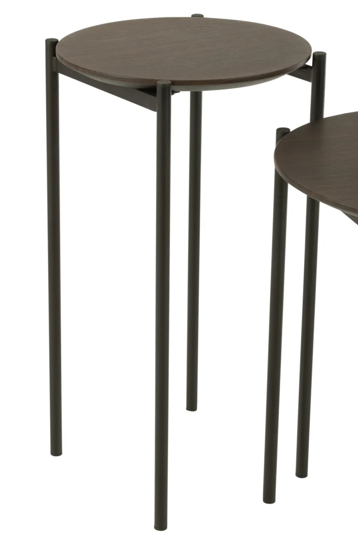 Twee Bijzettafel Bruin ronde bijzettafels (43 x 43 cm) met donkerbruine bladen en slanke zwart metalen poten, zo opgesteld dat de ene iets achter en rechts van de andere staat.