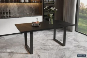 Een moderne eetkamer met UITVERKOOP - Tafel 'Nicola' 180 cm, een strakke rechthoekige tafel van zwart mangohout met minimalistische metalen poten, aangevuld met een vaas met witte bloemen, marmeren vloeren, ingebouwde planken en grote ramen met uitzicht op groen.