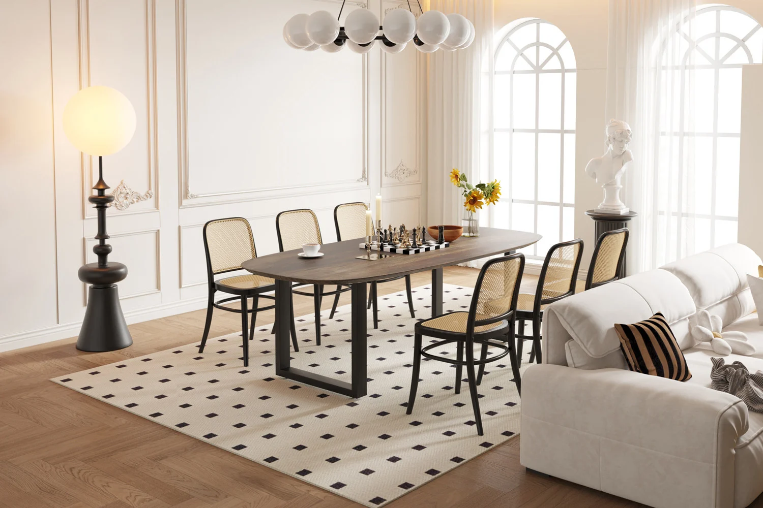 Een moderne eetkamer met de UITVERKOOP - Tafel 'Tommy' 220x100 cm Deens Ovaal U-Poot Mango hout Tabaco als schaaktafel, zes stoelen met geweven rugleuning, een crèmekleurige bank, staande lamp, klassieke buste, vazen met bloemen en hoge boogramen.