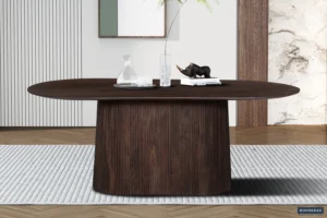 De Tafel 'Miguel' 200 cm Ovaal Mango hout Donkerbruin staat op een vloerkleed met structuur, met daarop een glazen karaf, drinkglas, twee boeken en een kleine zwarte neushoorn. Het moderne decor maakt de verfijnde setting compleet.