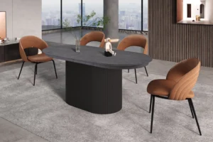 Een moderne eethoek met de 'Lagos' ovale uitschuifbare tafel van 180-220 cm in donkerbruin, vier tan gestoffeerde stoelen, een grijs vloerkleed, ramen met uitzicht op de stad en de tafel gedecoreerd met een glazen vaas met takken en een klein abstract beeldhouwwerk.