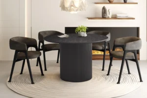 Een moderne eethoek met de Tafel 'Lagos' 120 cm Rond Decor Donkerbruin tafel, vier grijze stoelen met kussens, een wit vloerkleed met structuur, een decoratief plantenstuk, wandplanken met decor en een elektrische open haard op de achtergrond.