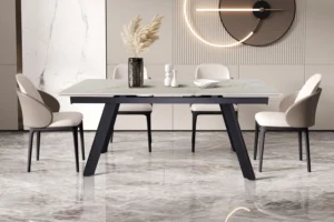 Een moderne eetkamer met de rechthoekige, lichtgekleurde uitschuifbare tafel 'Hera' (160-240 cm) in glanzend Shakespear Beige, vier beige stoelen, een vaas van pampagras, decoraccenten, marmeren vloeren en een ronde wandlamp op een beige muur.