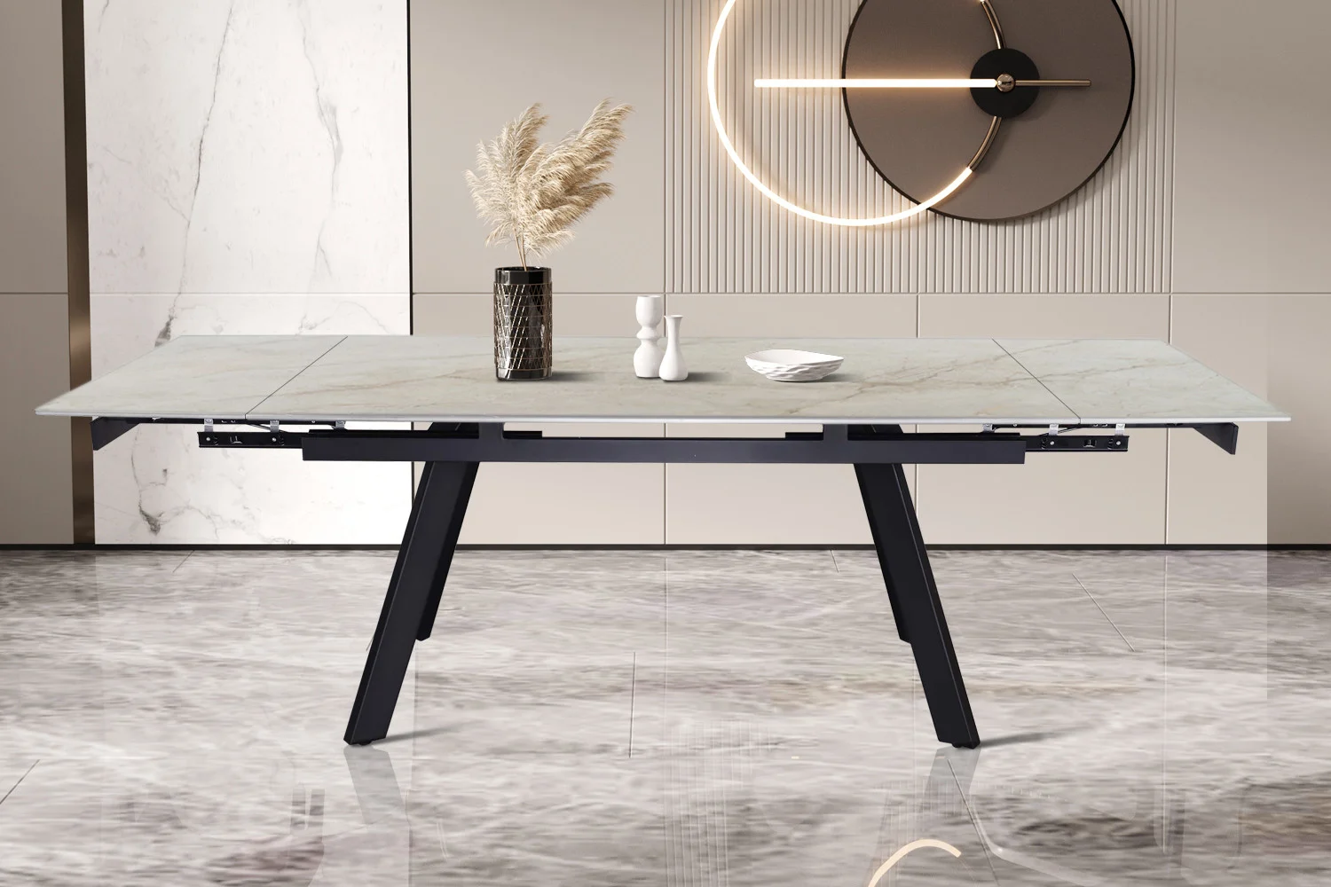 De Uitschuifbare tafel 'Hera' 160-240 cm, rechthoekig met een glanzend Shakespear Beige blad en zwarte schuine poten, staat op een glanzende marmeren vloer met licht beige muren, een vaas met pampasgras en een wandklok op de achtergrond.