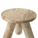 De Bijzettafel Beige 35 x 40 CM Rond Marmer is een kleine, ronde bijzettafel met een dik beige marmeren blad en drie brede, naar buiten gebogen cilindrische poten.