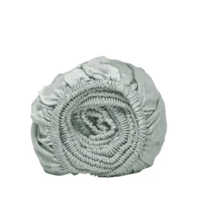 Oprolbaar lichtgroen hoeslaken van Tencel Lyocell op een witte achtergrond. Elastische randen zijn zichtbaar, zachte stof.