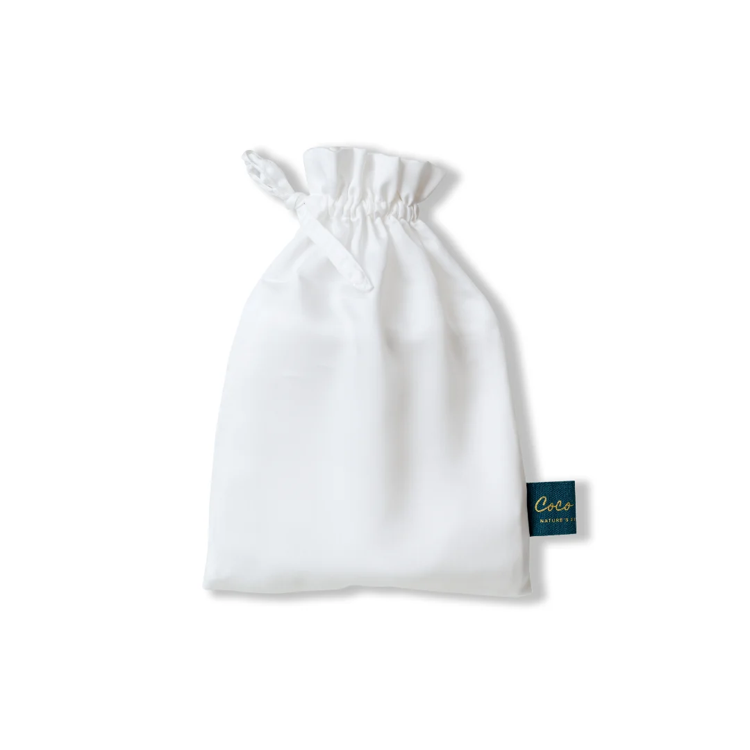 Witte bamboe kussensloop in een stoffen zakje, close-up. Zachte belichting, minimalistische stijl. Ideaal voor een hypoallergeen beddengoed.