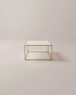 De Salontafel Messing Design Tijdloos Design is een minimalistische vierkante salontafel met een dun, goudkleurig metalen frame en een wit blad, afgebeeld tegen een effen, lichtgekleurde achtergrond.