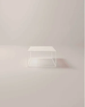De Salontafel Wit, een minimalistische witte vierkante salontafel met een onderstel in open frame en een massief blad, staat in het midden van een lichte neutrale kamer met een zacht kleurverloop op de achtergrond.