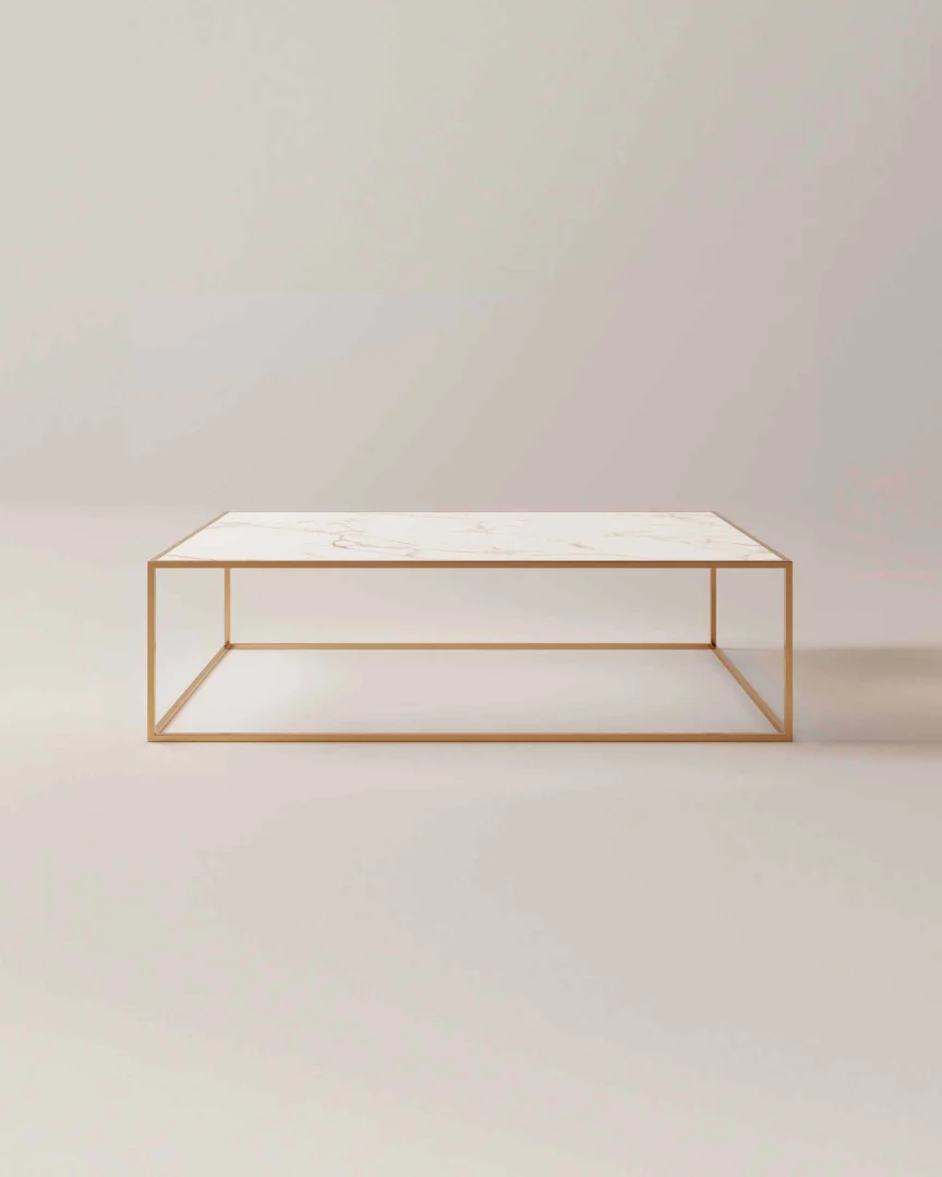 De Salontafel Messing Design heeft een vierkant wit marmeren blad en een slank goud metalen frame, tegen een eenvoudige lichte achtergrond.