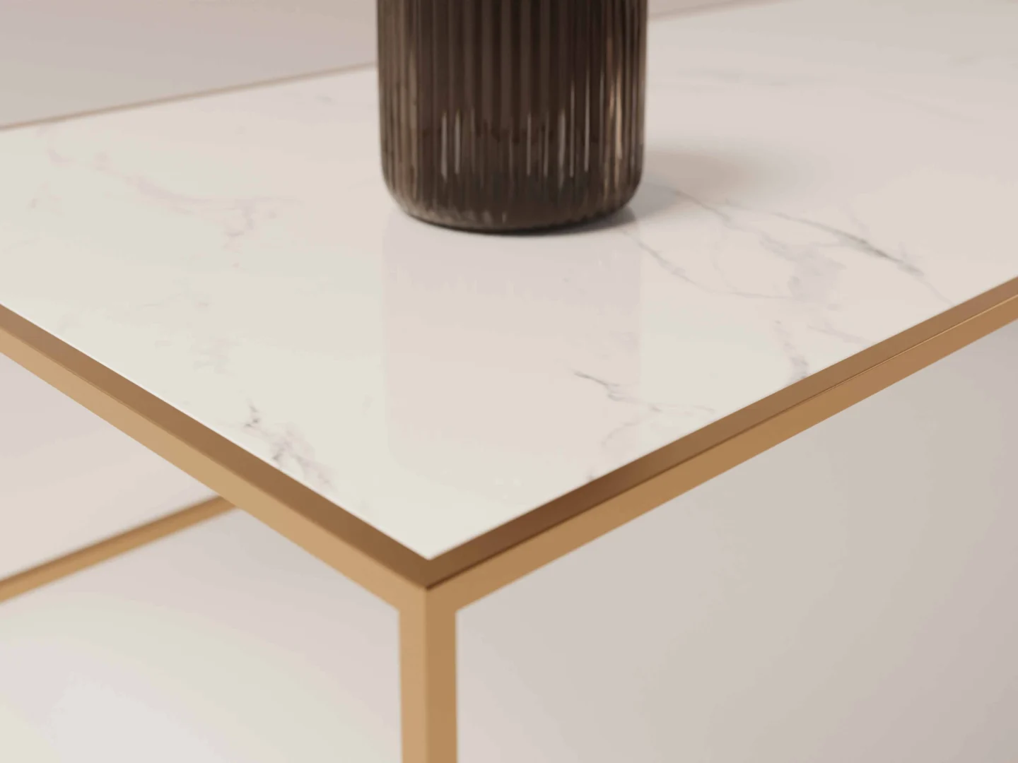 Een close-up van de Salontafel Messing Design toont het goudmetalen frame en het blad met wit marmerpatroon. Een donkere, geribbelde vaas rust gedeeltelijk op de tafel en creëert zo een minimalistische en elegante setting.