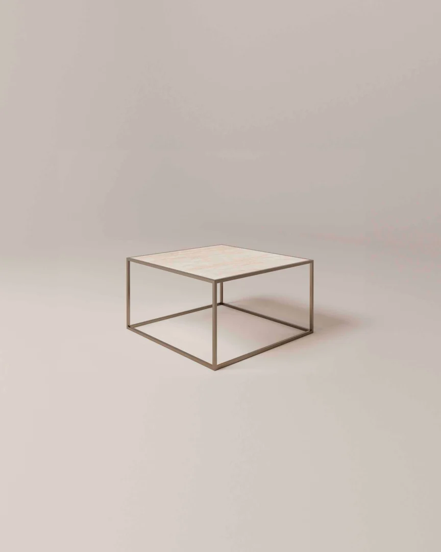 De Salontafel Brons Rond is een minimalistische ronde salontafel met een dun metalen frame en een lichtgekleurd blad tegen een effen, neutrale achtergrond.