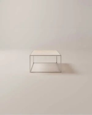 De Salontafel Tijdloos Design is een minimalistische vierkante salontafel met een licht houten blad en een slank metalen frame, tegen een effen, lichte achtergrond.